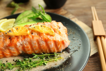 Poster - Plate with slice of delicious salmon and fish sauce on table