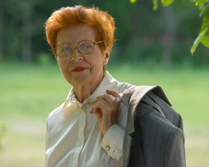 Portrait of business woman aged against the background of the park.