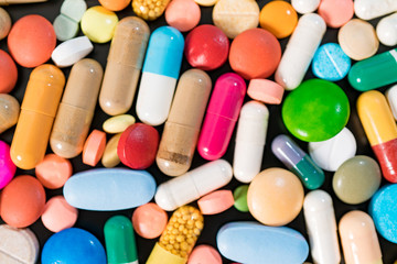 Poster - Multicolored pills and capsules on a black background