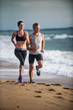 © jackfrog - A couple wearing sportswear is running on the beach