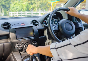 The woman in the car is driving. The two sides of the garden is surrounded by fences.