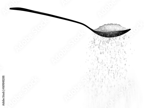 Fotografie, Obraz Sugar or salt falling from a spoon isolated on white