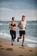 © jackfrog - A couple wearing sportswear is running on the beach