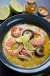 Close-up of spicy Thai green curry soup with shrimps and shiitake mushrooms, vertical shot