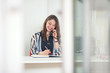 Cheerful young businesswoman is talking on the phone while working at her desk