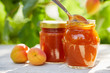 Apricot jam in glass jars with fresh fruit on a wooden table
