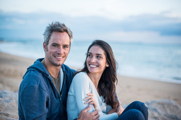 Beautiful couple sitting at the beach watching the sunset