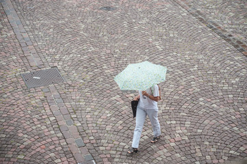 Wall Mural - femme avec parapluie traversant une place pavés sous la pluie