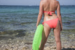 © grufnar - wet woman standing by the sea in a pink swimsuit with green life preserver