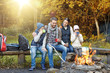 © Syda Productions - happy family sitting on bench at camp fire