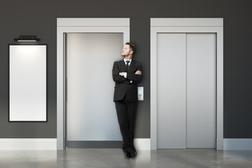 Wall Mural - Thoughtful businessman with elevators and banner