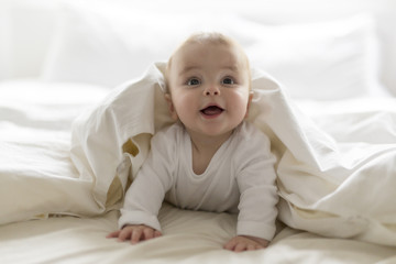 cute happy 7 month baby girl in diaper lying and playing