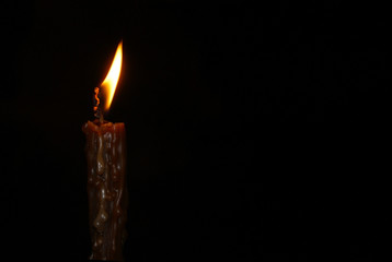 Flame of a lonely burning church wax candle isolated on a black background