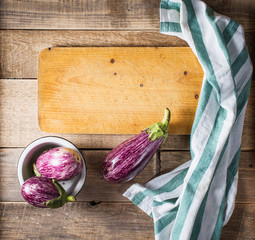 Wall Mural - Some eggplants, garlic and red onion with a wooden board. Copy past. Top view