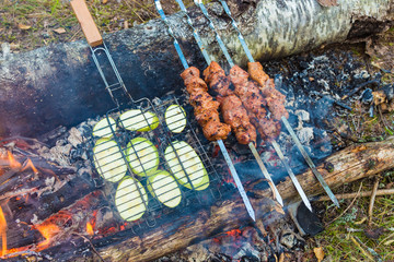 Wall Mural - Close up pork meat grilled on skewers. Cooking shashlik in the forest. Grilling pork on coal