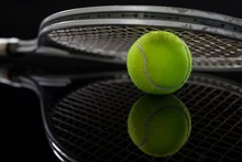 Close Up Of Racket On Fluorescent Yellow Tennis Ball With