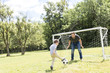 © Louis-Paul Photo - Young father with his little son playing football on football pitch