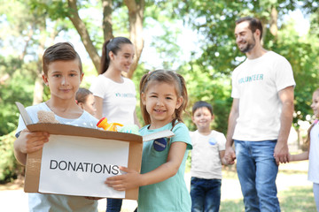 young volunteers and children with box of donations outdoors
