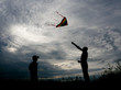 © ruslanshug - Adult man and child launch a kite against a beautiful summer sunset