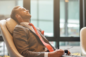 Professional businessman having a nap in the departure lounge