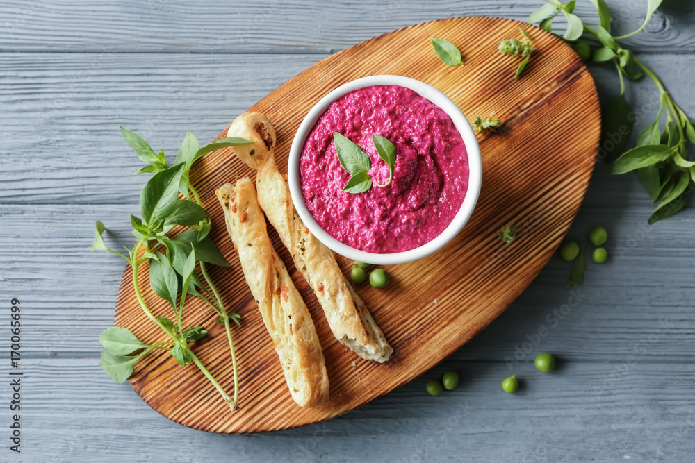 Bowl with delicious creamy beet hummus on wooden board