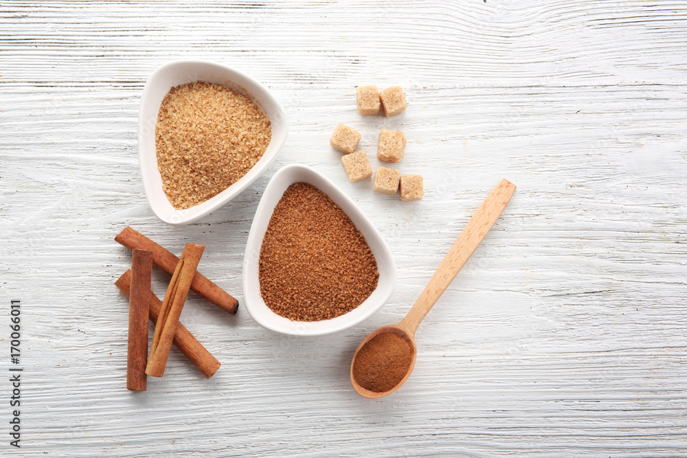 White bowls with cinnamon sugar and sticks on wooden background