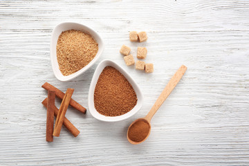 Wall Mural - White bowls with cinnamon sugar and sticks on wooden background