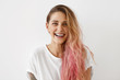 © WHstudio Leushin N - Picture of stylish trendy-looking young woman of European appearance wearing her messy pastel pink hair to the side smiling broadly, demonstrating her perfect white teeth. Youth and happiness