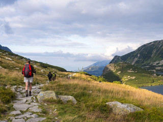 people with backpacks go on the road in the mountains.