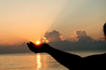 Silhouette human open empty hands with palms up over sun on sunrise background