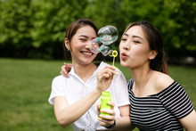 Cute Asian Girlfriends Making Soap Bubbles In The Park.