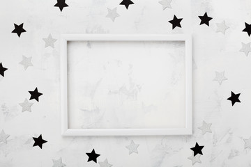 White picture frame with black and silver stars around for fashion blogging mockup. Top view and flat lay.