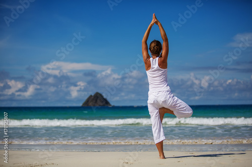 Fotografia Caucasian woman practicing yoga at seashore of tropic ocean