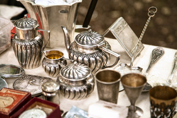 antique silver teapots, creamer and other utensils at a flea market. old metal tableware collectible