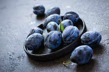 Dark Blue Plums In Cast Iron Plate On Black Background Closeup