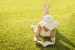 © Thiago Santos - Linda mulher lendo um livro no gramado verde, sol de verão.