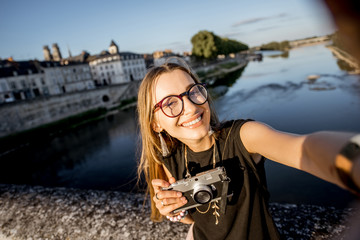 Wall Mural - Young woman tourist making selfie photo on the beautiful cityscape background in Orleans, France