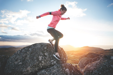 Athletic girl running in the mountains at sunset against the backdrop of a beautiful landscape. Sport tight clothes. Intentional motion blur.