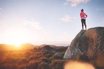 Athletic girl examines mountain landscape for training on running at sunset. Sport tight clothes. 