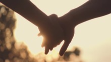 Close Up Of Two Lovers Joining Hands. SLOW MOTION 240 Fps. Detail Silhouette Of Man And Woman Holding Hands Over The Sunset Lake Background. Couple Trust, Love And Happiness Concept. 