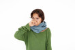 © shurkin_son - Healthcare, unwellness, disease, illness and sickness concept. Uunhappy young brunette Latin woman having cold or flu, trying to warm up, wearing sweater and scarf, covering nose while sneezing