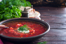 National Traditional Ukrainian Soup Made From Beets And Vegetables - Borscht With Sour Cream And Fresh Herbs In A Clay Bowl, Horizontal, Copy Space