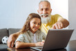 © zinkevych - Little girl and her grandfather watching a cartoon on laptop