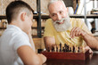 © zinkevych - Charming senior man moving a pawn and smiling at grandson