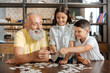 © zinkevych - Siblings and their grandfather joining three jigsaw puzzle pieces