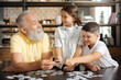© zinkevych - Siblings and their grandfather having fun while doing puzzle