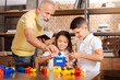 © zinkevych - Grandfather helping grandchildren build a tower with construction set