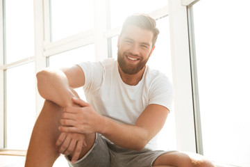 Smiling bearded man near the window at home