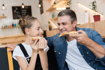 father and daughter eating pizza