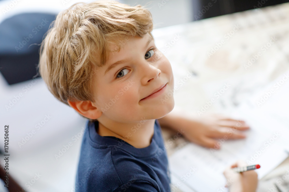 Happy smiling kid boy at home making homework writing letters with colorful pens - obrazy, fototapety, plakaty 